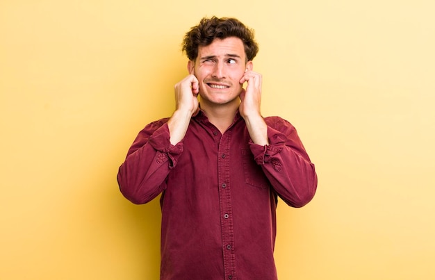 Er boos uitzien, gestrest en geïrriteerd zijn en beide oren bedekken voor een oorverdovend lawaai of luide muziek