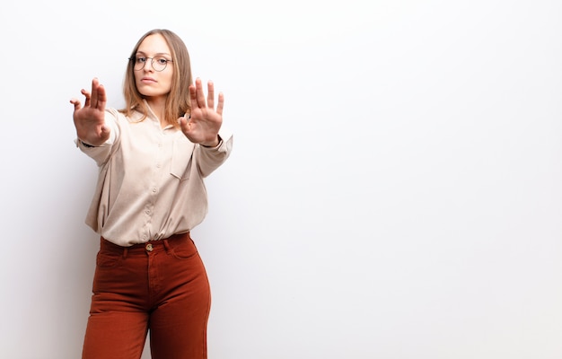 er ernstig, ongelukkig, boos en ontstemd uit te zien en de toegang te verbieden of te stoppen met beide open handpalmen