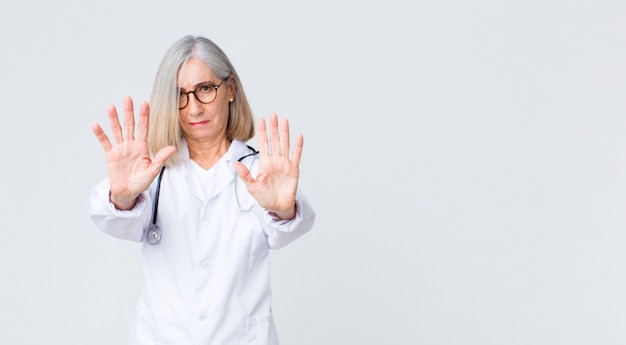 Er ernstig, ongelukkig, boos en ontstemd uit te zien en de toegang te verbieden of te stoppen met beide open handpalmen