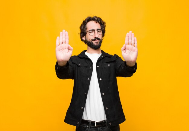 Foto er ernstig, ongelukkig, boos en ontstemd uit te zien en de toegang te verbieden of te stoppen met beide open handpalmen