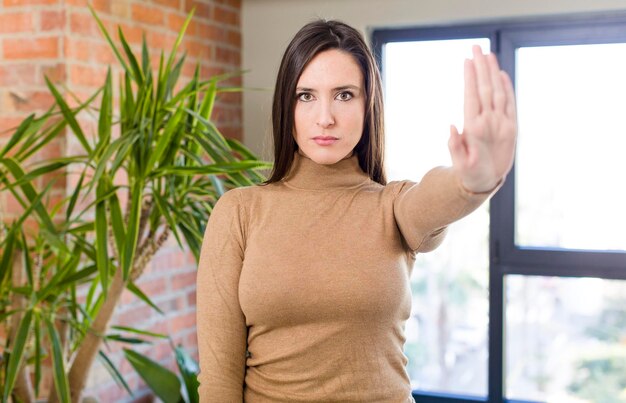 Foto er ernstig streng ontstemd en boos uitzien met een open handpalm die een stopgebaar maakt