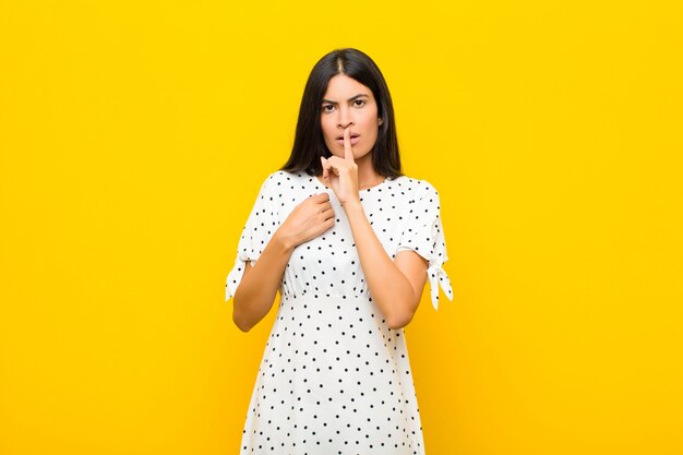 er ernstig uitziet en er met de vinger tegen de lippen tegen gedrukt, eist stilte of stilte en houdt een geheim