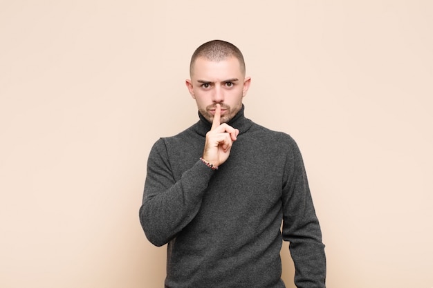 er ernstig uitziet en er met de vinger tegen de lippen tegen gedrukt, eist stilte of stilte en houdt een geheim