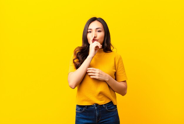 er ernstig uitziet en er met de vinger tegen de lippen tegen gedrukt, eist stilte of stilte en houdt een geheim