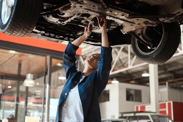 Er gaat niets boven het kunnen repareren van iets met je blote handen Shot van een vrouwelijke monteur die onder een opgeheven auto werkt