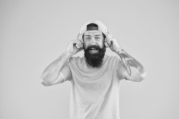 Er is muziek voor elke man Bebaarde man in trendy hipsterstijl glimlachend op gele achtergrond Gelukkige man met baard en snor met moderne koptelefoon Brutale man geniet van het luisteren naar muziek