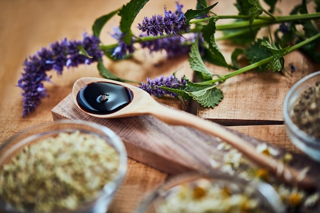 Er is veel dat je kunt doen met lavendel Shot van een houten lepel met donkere vloeistof erin omringd door verse lavendel op een tafel