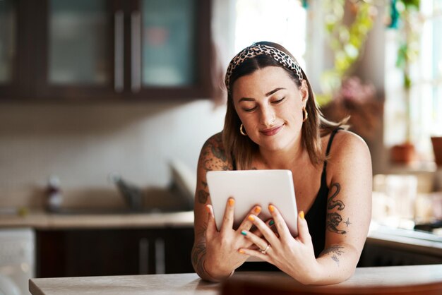 Er is veel waar we ons op kunnen vinden op sociale media Shot van een jonge vrouw die thuis een digitale tablet gebruikt in de keuken