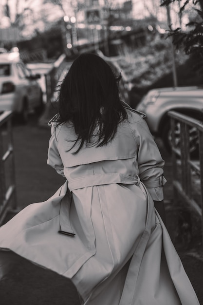 Er loopt een vrouw over straat met een witte jas aan.