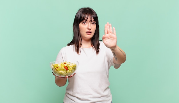 er serieus, streng, ontevreden en boos uitzien met een open handpalm die een stopgebaar maakt