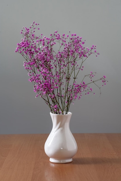 Er staan droogbloemen in een vaas op tafel.