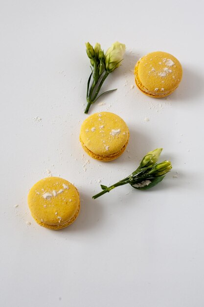 Er staan macarons op tafel. In de buurt zijn gele bloemen.