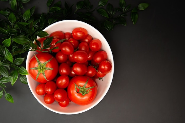 Er zijn verschillende tomaten op een witte plaat. Het is een zwarte achtergrond