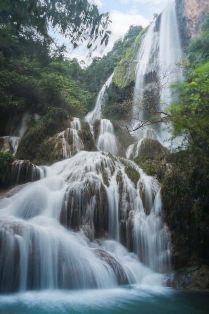 Водопад Эраван 7-й этаж с водой, текущей через натуральный камень в тропическом лесу в национальном парке, Канчанабури, Таиланд