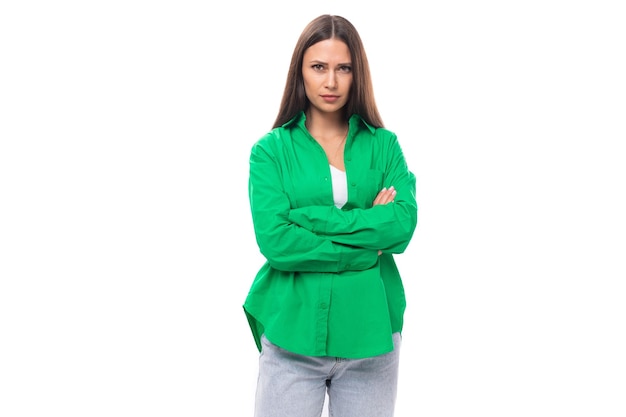 Ernstig jong europees vrouwelijk model met goed verzorgd zwart haar en make-up gekleed in een groen shirt