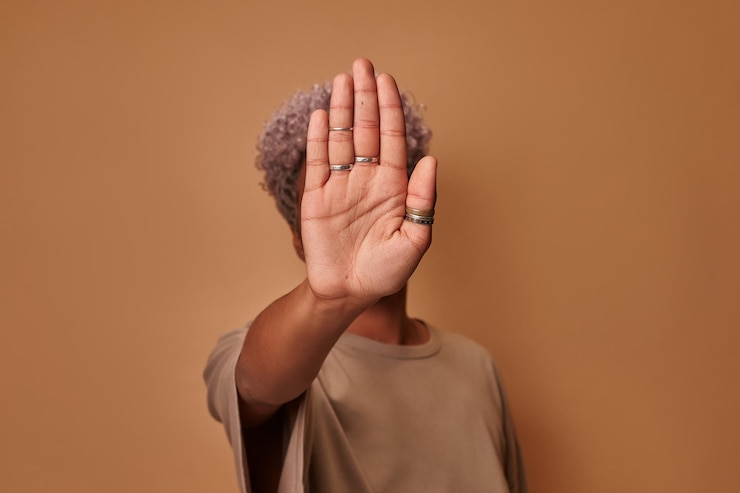 Foto ernstige afro-amerikaanse vrouw bedekt zichzelf met haar handpalm toont vol vertrouwen een verbodsgebaar stop en geen tekenen schudt haar hoofd jonge etnische vrouw tegen geweld verdedigt persoonlijke grenzen