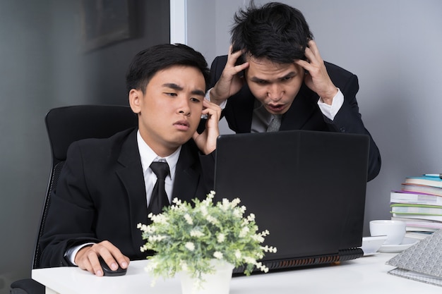 ernstige benadrukt twee zakenman met behulp van laptop aan het werk project