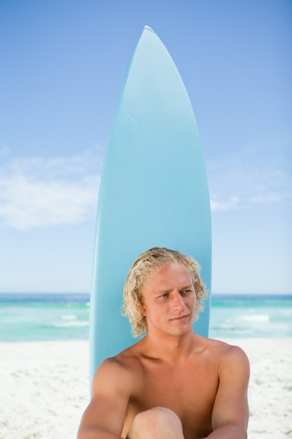 Ernstige blonde mensenzitting voor zijn surfplank