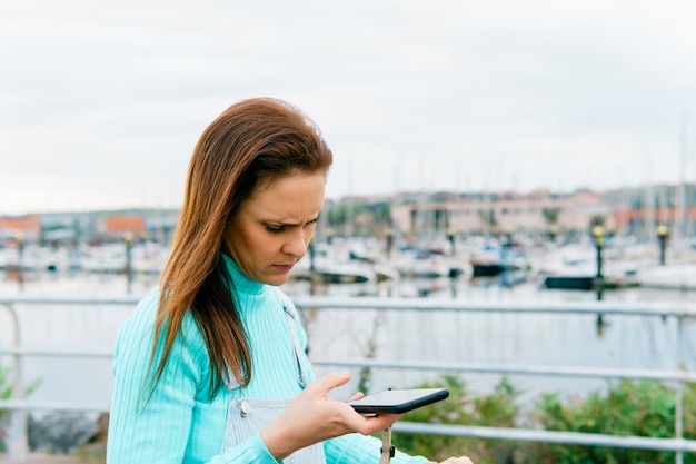 Ernstige en bezorgde duizendjarige jonge volwassen vrouw die nieuws op smartphone ontvangt