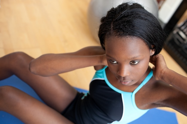 Ernstige etnische vrouw in gymnastiekkleren het uitwerken