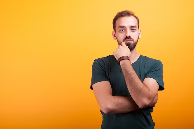 Ernstige handsmon man poseren in studio op gele achtergrond