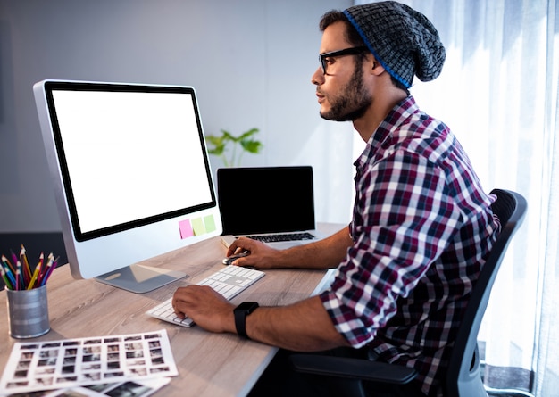 Ernstige hipster die bij computerbureau werkt