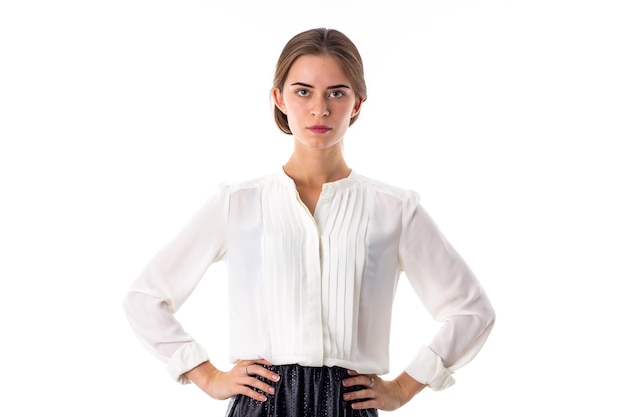 Ernstige jonge vrouw die witte blouse en zwarte rok op witte achtergrond in studio draagt
