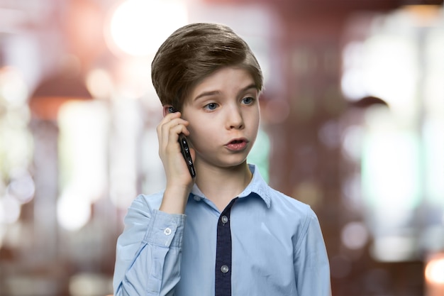 Ernstige kleine jongen praat aan de telefoon