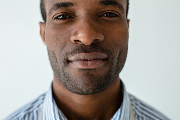 Ernstige knappe afro-Amerikaanse man die naar voren kijkt terwijl hij tegen een witte muur staat