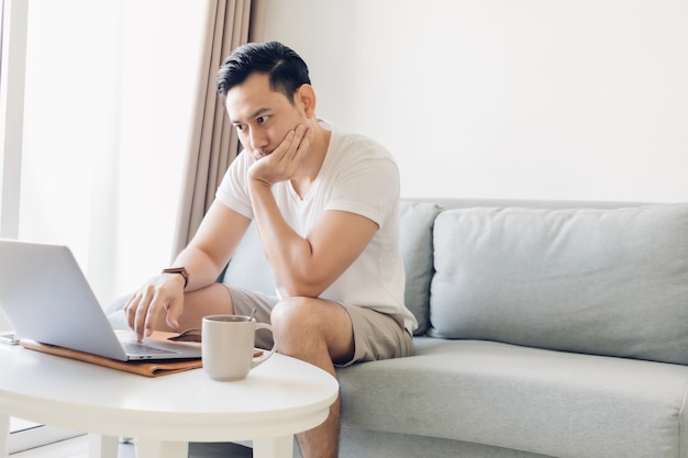 Ernstige man werkt op zijn laptop in de woonkamer.