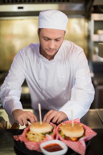 Ernstige mannelijke chef-kok die hamburger in commerciële keuken voorbereidt