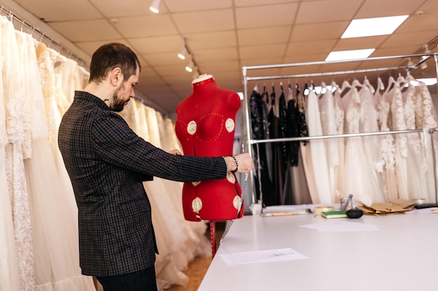 Ernstige mannelijke modeontwerper tekening schets van nieuwe kleding collectie in etnische design studio man kleermaker maken lijn werken met penseel of potlood op persoonlijk bureau borduurpatroon ontwikkelen