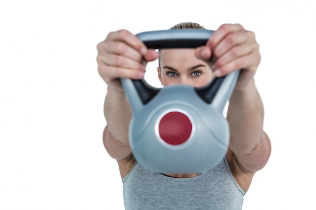 Ernstige spiervrouw die kettlebell opheffen