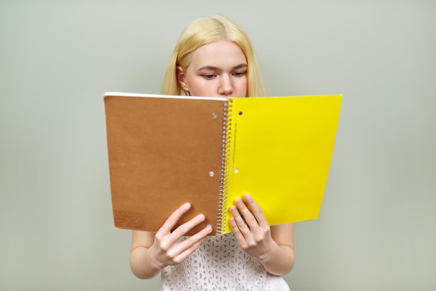 Ernstige student die notitieboekje leest close-up gele dekkingsplaats voor tekst Meisjestiener op lichte studioachtergrond