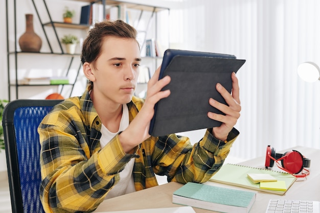 Ernstige tiener die video bekijkt, artikel leest of toepassing op digitale tablet gebruikt