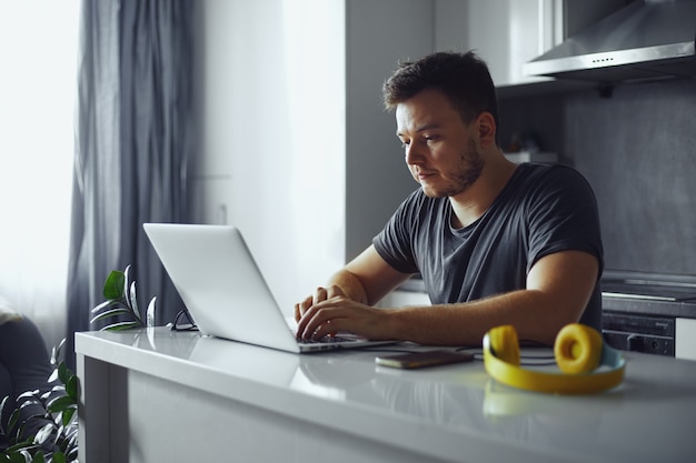 Ernstige volwassen man freelancer met behulp van laptop die online studeert en thuis werkt