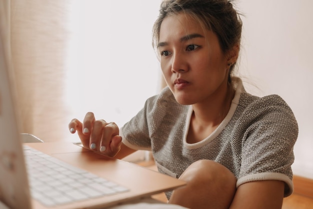 Ernstige vrouw die met haar laptop in de slaapkamer werkt