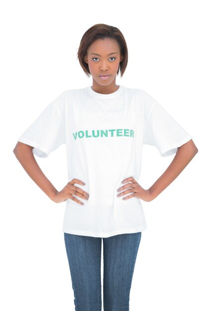 Ernstige vrouw met handen op heupen die vrijwillige t-shirt dragen