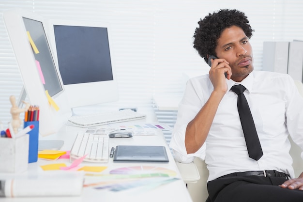 Ernstige zakenman die bij zijn bureau aan de telefoon werkt