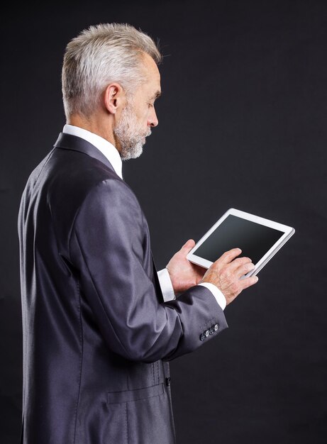 Ernstige zakenman die het digitale tabletscherm bekijkt.