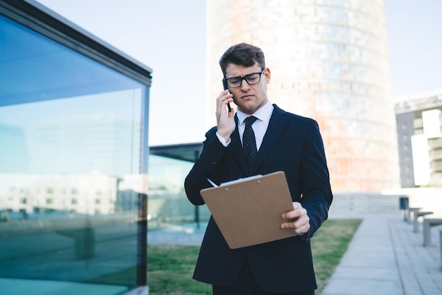 Ernstige zakenman die op straat aan de telefoon spreekt