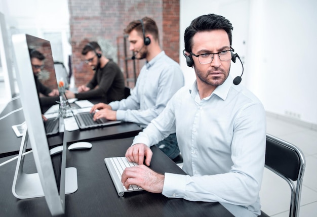 Ernstige zakenman in een headset die aan een bureau zit