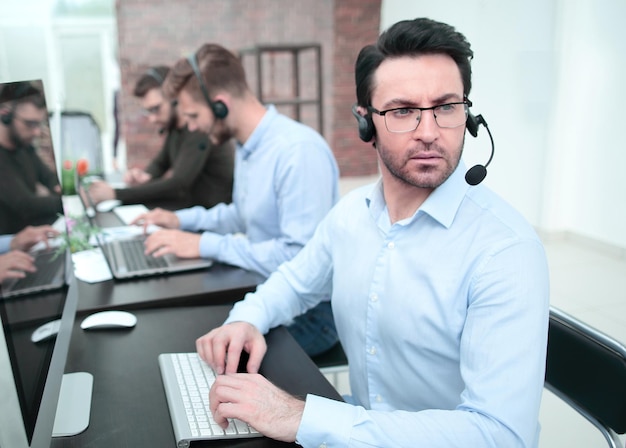 Ernstige zakenman in een headset die aan een bureau zit