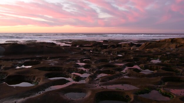 カリフォルニアの夕焼け空の水面反射における侵食された潮溜まりの岩石形成