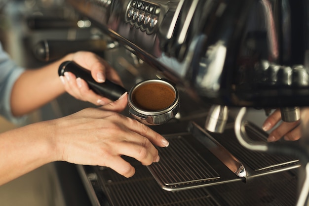 Ervaren barman die espresso maakt in een modern koffiezetapparaat. Close-up van vrouwelijke hand die verkwikkende drank voorbereiden. Klein bedrijf en professioneel koffiebrouwconcept