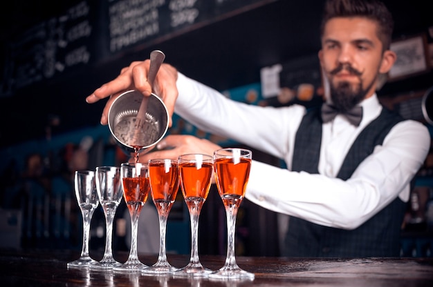 Ervaren bartending gieten van verse alcoholische drank in de glazen in de nachtclub