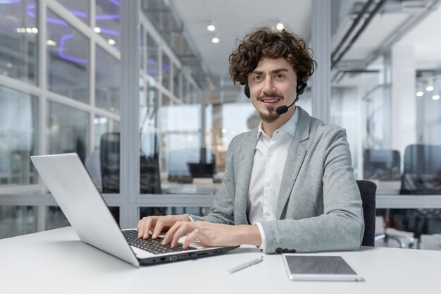 Ervaren mannelijke zakelijke professional met krullend haar en headset werken op een laptop in een