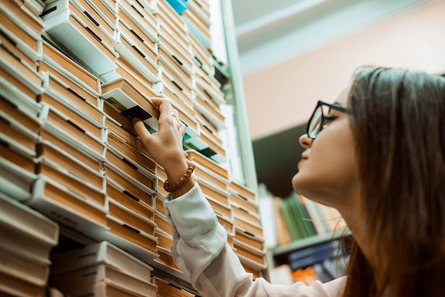 Ervaren professionele aantrekkelijke vrouwelijke bibliothecaris die een boek meeneemt voor een lezer