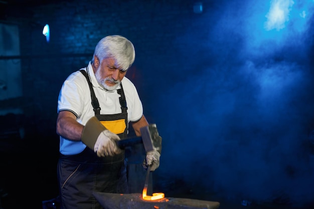 Ervaren smid die gesmolten metaal handmatig smeedt