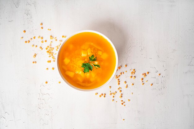 Erwtensoep op een lichte achtergrond. Erwtensoep in een witte kom. Een kom soep. Peterselie, pepermengsel, saus, brood. Hoge kwaliteit foto